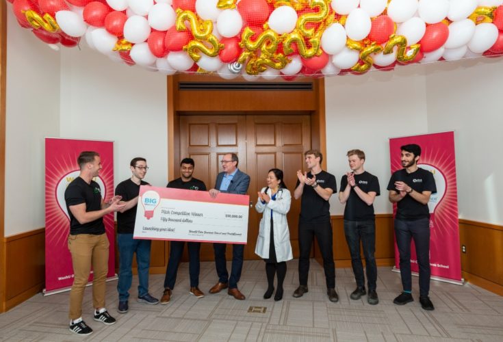 Judges hand the oversized $50,000 check to team members from PedalCell just before the balloon-drop at the 2022 BIG IdeaBounce powered by Poets & Quants.